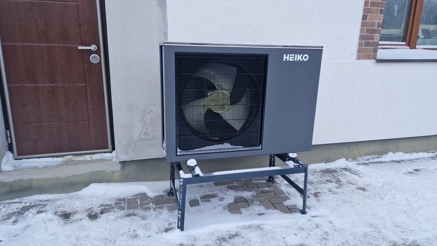 Oras–vanduo šilumos siurblio monoblokas, sumontuotas prie namo sienos žiemą